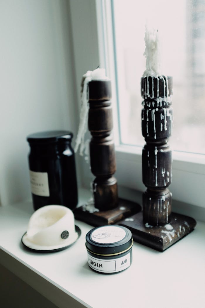 Aesthetic arrangement of melted candles on wooden holders by a window sill.