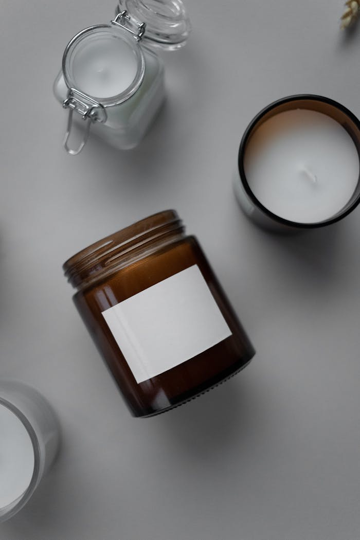 Top view of assorted candles in jars on a neutral background, creating a minimalist aesthetic.