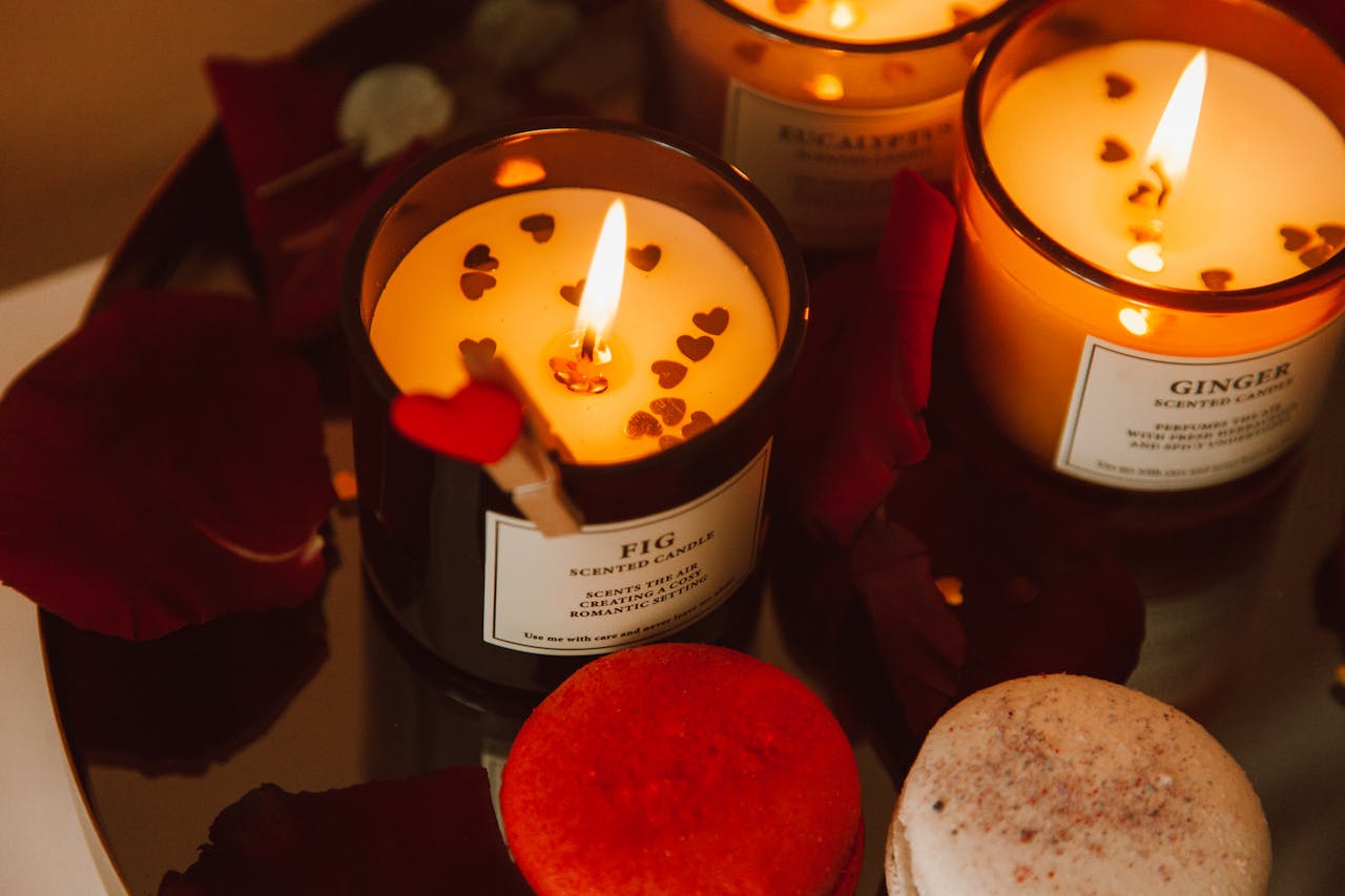 Warm candlelit scene with fig and ginger scented candles surrounded by rose petals and macarons.